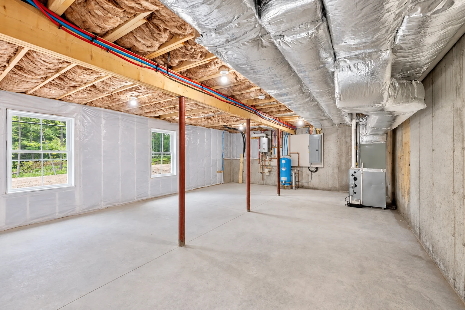 Basement with insulated ceiling joists, foil-wrapped ducts, and white sheeting covering the walls.