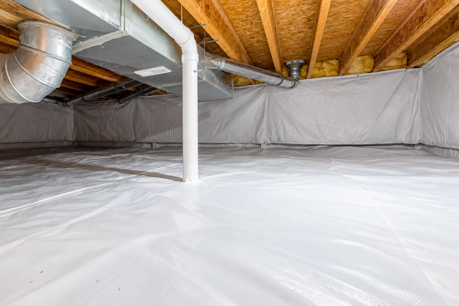 Crawl space with white vapor barrier covering the floor and walls beneath exposed wooden joists and ductwork.